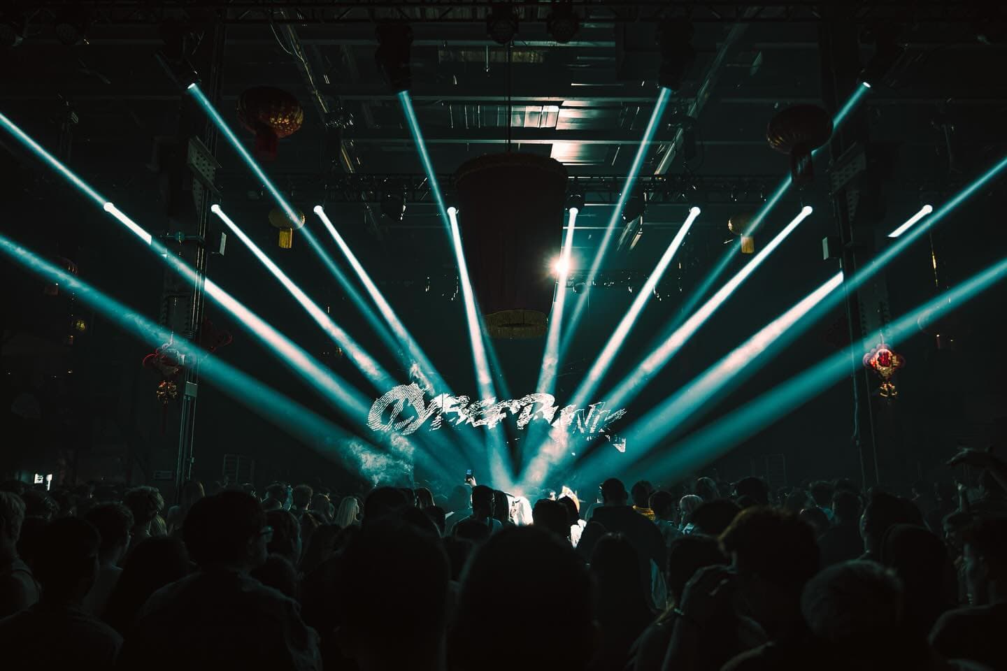 Stage beams fanning out over a packed crowd under the Cyberpunk logo
