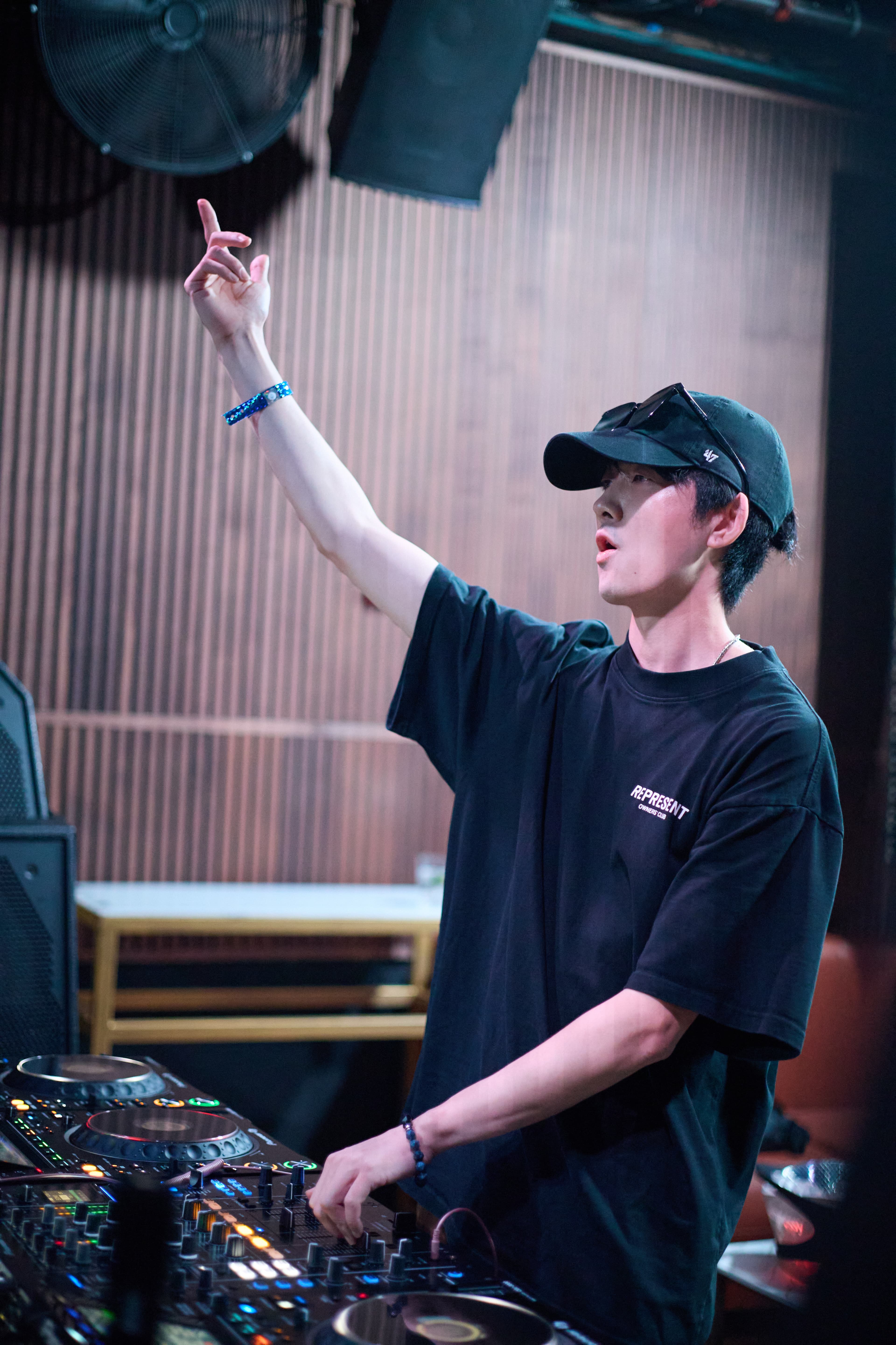 Ezzek raising his hand behind the decks during a club set